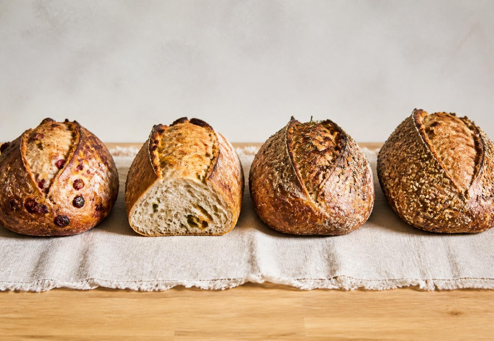 Four seasonal sourdough loaves lined up on linen